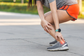 a women felling achilles attachment pain while running