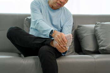 a man in blue shirt having pain on his foot