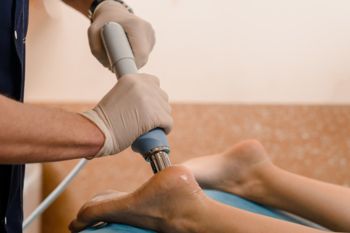 A podiatrist performing shockwave therapy on a patient's feet
