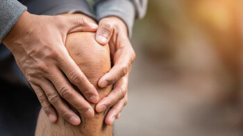 person holding his knee, expressing discomfort